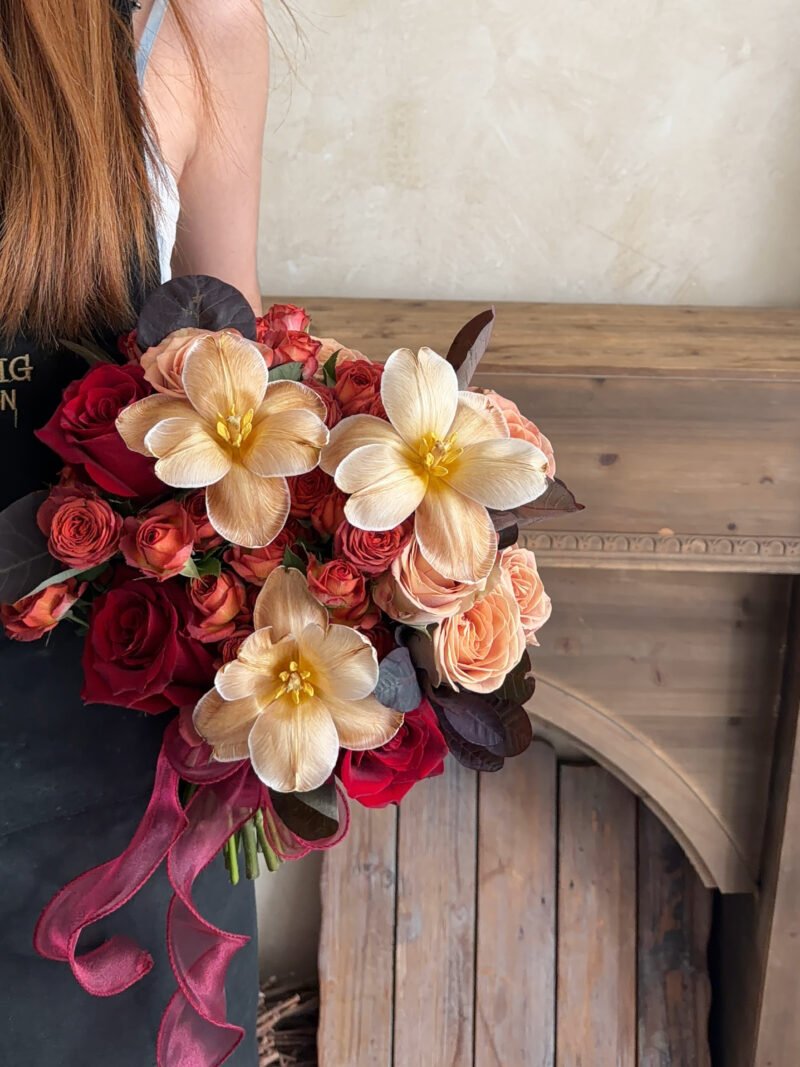 Full view of Rosé Éternelle bridal bouquet with red, terracotta and champagne flowers